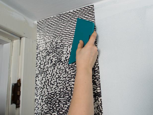 Once paper is properly placed, smooth out bubbles and wrinkles with a rubber smoother or wallpaper brush.  Smooth from the center of the paper toward the edges, pressing out extra glue and air.  The squeeze-out will drip down the walls, so itâs a good idea to have an old towel on the floor to sop it up.  Once smoothed, wipe paper clean of glue with a clean, damp cotton cloth or wallpaper sponge.  Rinse cloth or sponge and wring out regularly to keep it clean.  At this point, paper will feel wet, but shouldnât be dripping or have visible glue on the surface.