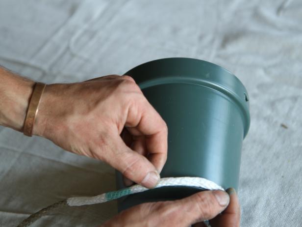 Apply hot glue to the bottom edge of the plastic pot, and place one end of the rope on top of the hot glue. Allow glue to cool, securing the rope to the pot.