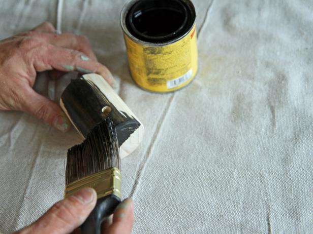 Apply ebony stain to the wood dowel, and let it penetrate for three minutes.