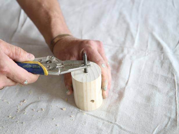 Insert a 1/4” x 2” dowel screw into the pre-drilled hole, and tighten down one inch into the dowel using long-nose locking plyers.