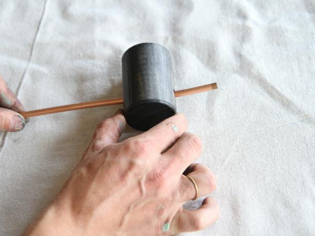 Slide the copper pipe through the hole in the wood dowel.