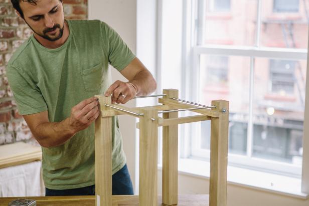 Secure threaded rods to table base using nuts.