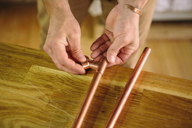 Create a triangular shape with copper piping to make a sconce.