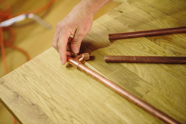 Create a triangular shape with piping to make an industrial-style sconce.