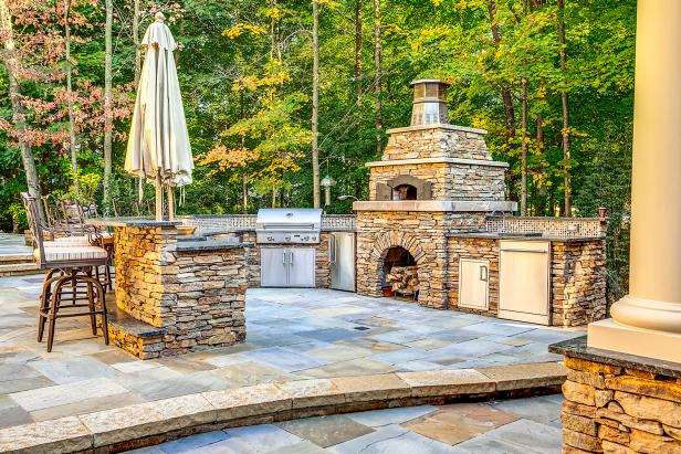 Natural Stone Outdoor Kitchen Featuring Pizza Oven, Stainless Steel Grill and Bar Seating Natural Stone Outdoor Kitchen Featuring Pizza Oven, Stainless Steel Grill and Bar Seating