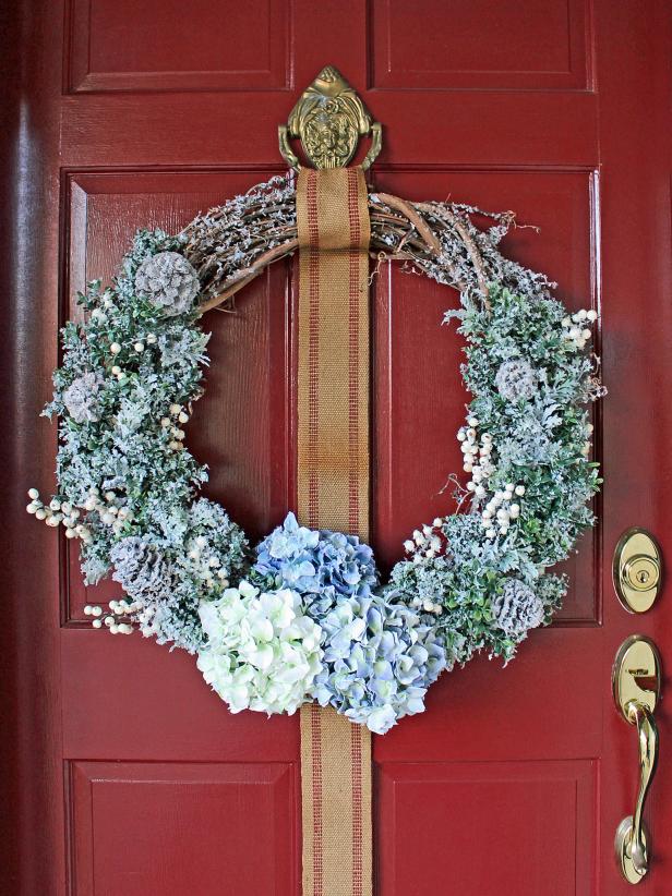 Add faux greenery, flowers, berry sprigs and glittered pinecones to a grapevine wreath then cover with faux snow to give your front door a cheery update during winter months.
