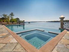 Slate pavers on the pool deck surround this luxurious infinity pool. Pillars at the edge of the pool support stone bowls with fire, which makes for a romantic nighttime swim.  