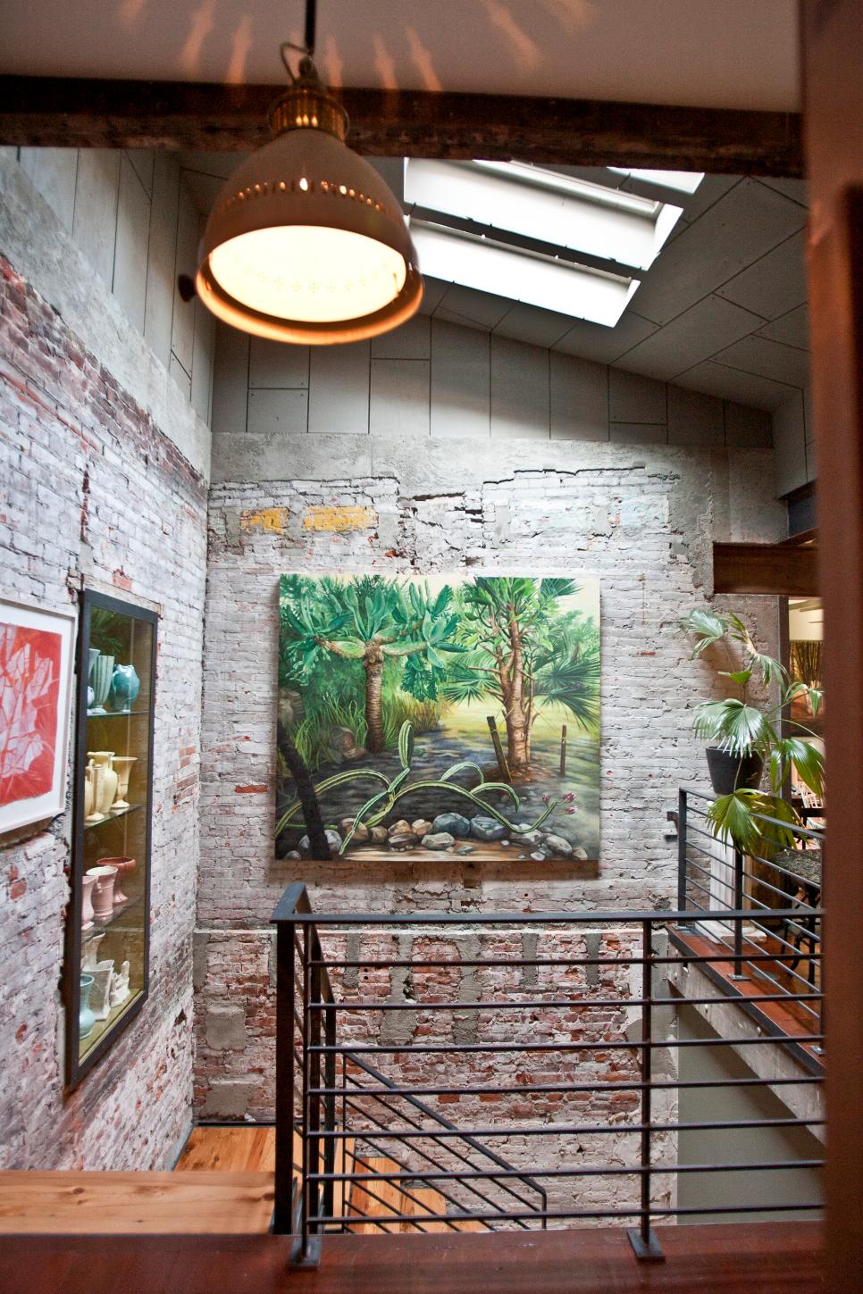Industrial Stairway Features Whimsical Art Staircase With Exposed Brick Walls and Green Tropical Artwork