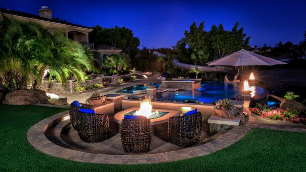 Stone Tile Fire Pit Patio Above Luxurious Swimming Pool and Tropical Landscaped Yard Stone Tile Fire Pit Patio Above Luxurious Swimming Pool and Tropical Landscaped Yard