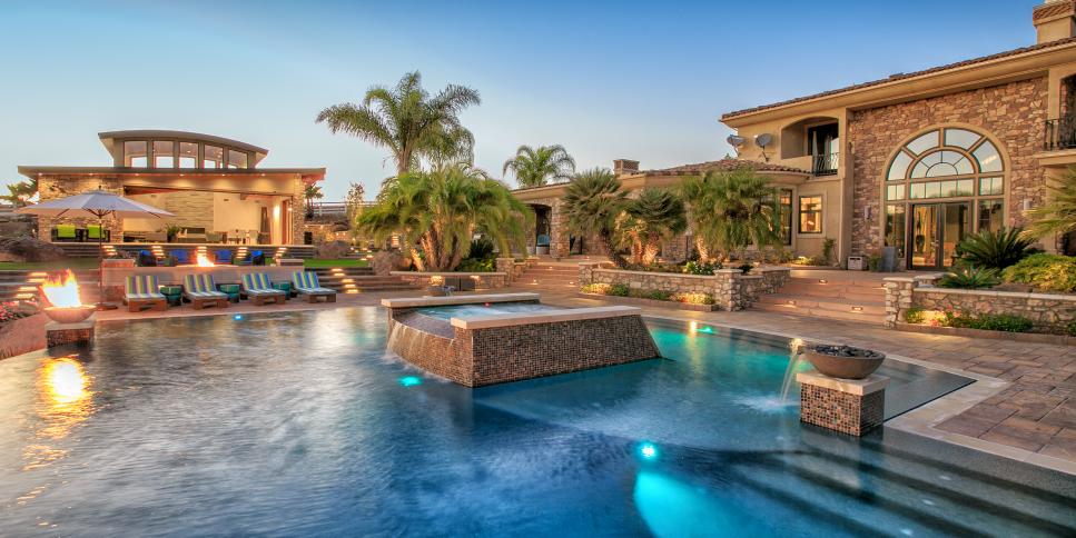 Swimming Pool With Hardscape Levels, Waterfall Features and Striped Lounge Chairs Tropical Backyard Swimming Pool