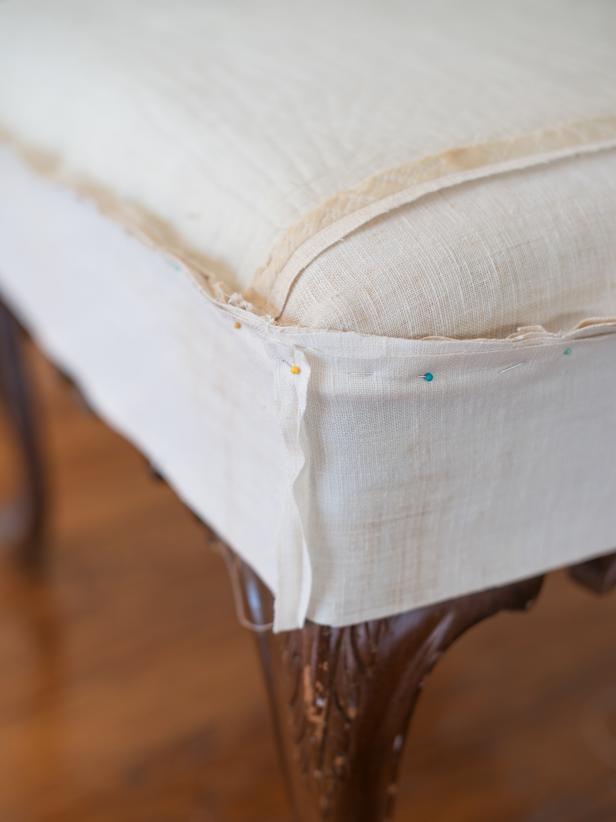 Position ottoman top face down on ottoman. Pin top to side “band”, sandwiching piping in between. Finished piping side should be inside; facing ottoman, and all raw edges should be pointing out, since slipcover is being assembled inside out. Sew along pins, removing along the way. Where the ends of piping meet, just cross the ends and let them “disappear” into the seam. Try the slipcover on right side out to make sure everything is fitting properly.