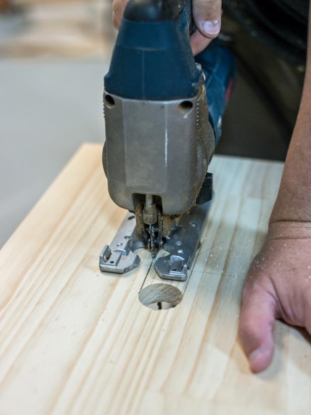 Use measuring tape to determine center point of stool top. For a 3” wide handle, measure and mark 1 ½” out length-wise from center point to the left and right. Use ½” forstner bit affixed to a drill to drill a hole just to the inside of both of those marks. Use a jig saw to cut between the two holes, completing the handle cut out.