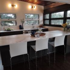 Sharp Modern Kitchen With Long White Marble Countertop, Boxy White Bar Chairs and Contrast Color Scheme 