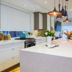 Bright White Kitchen With Assorted Pendant Light Shapes Over Long Island and Wood Topped Barstools