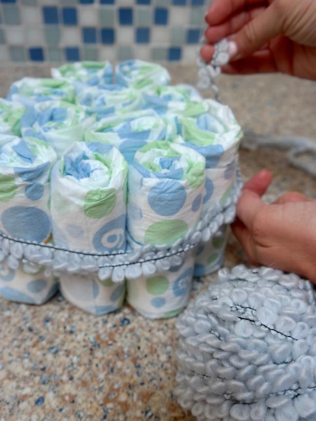How to Make a Diaper Cake Cover the rubber bands with your choice of ribbon or decorative trim.