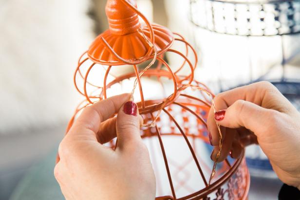 Once the battery pack is dry to the touch, you’re ready to place the lights in the birdcage. If your lights are super long, fold the string back on itself and twist the loose ends together to half the string which will save time on the weaving process. To start, place the battery pack in the bottom of the cage, then pull the end of the light string all the way through the top of the cage and begin weaving.