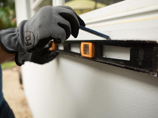 Now you’re ready to attach the bar to the house. Begin by marking where the bar will go with a level. Next, pre-drill and add any necessary anchors depending on what type of exterior cladding your home has, in our case we used heavy duty concrete anchors to secure the bar to the house.