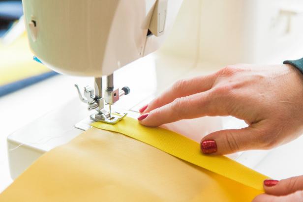 Next, fold and iron a hem on the outdoor fabric which is the back of the pillow cover. Then using a straight stitch, hem the coordinating edges.