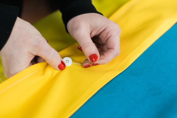 Using a needle and white thread, secure a few buttons to the flap for a little extra decorative flair, but this is totally optional. Space them equally along the flap.
