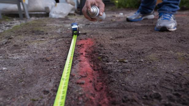 Using a measuring tape and spray paint, mark the perimeter of the new patio space