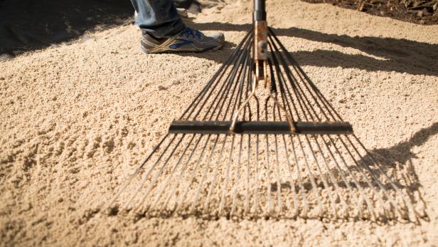 Add a layer of sand on top of the weed block material and rake, then tamp down flat, making the sure the surface remains level