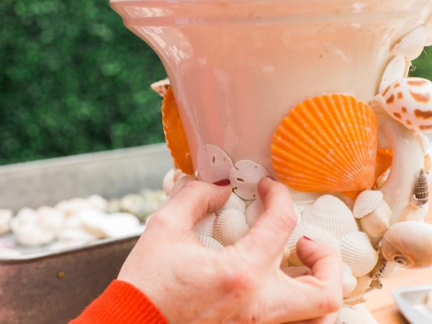 As you work, flip the urn upside down for better access to the urn’s surface when necessary. Add glue to the back of each sand dollar and push into place, varying the size of the sand dollars as you work. Sand dollars work great on the flatter surfaces of the vessel. You can also flip the sand dollars facing in the wrong direction, depending on the shape of your vessel so that they lay flat. Think of it like putting a puzzle together.