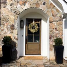 Cottage Entryway with Stone, Boxwoods and Weathered Brown Door
