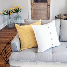 Mid-Century Modern Sofa With Yellow and White Throw Pillows in Country Living Room With Distressed Wood Door 