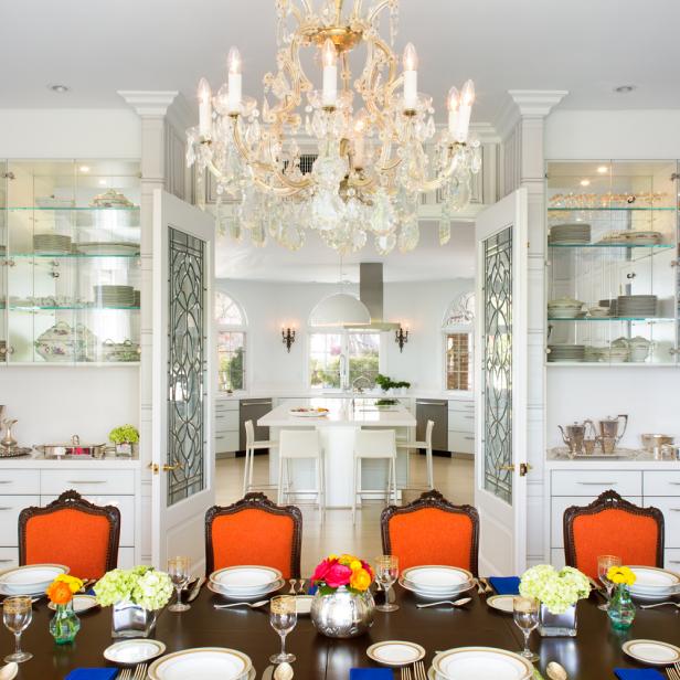 Lavish Transitional Dining Room With Crystal Chandelier, Orange Dining Chairs and Glass China Shelving Lavish Transitional Dining Room With Crystal Chandelier, Orange Dining Chairs and Glass China Shelving