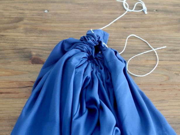 Pull the rope through the slit on the top right corner. Gather the sheet as tight as possible on the rope and tie both ends of the rope together.