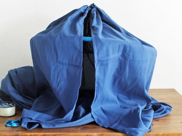 Drape the sheet over the hula hoop and glue the opening of the sheet to the hoop to secure it. Hang from the ceiling using the screw-in hook.