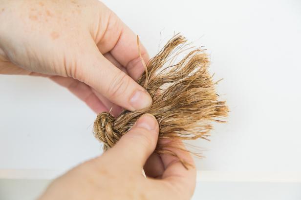 Once the bottom shelf is hung, tie off the ropes into a knot on either side, then trim them with a utility knife. For an interesting texture, you can pull apart the ends of the ropes for a fringed look. Now you’re ready to hang the shelf- just be sure to use the proper hardware and anchors! HINT- If you hang the shelf in a bathroom, over time the steam will help the rope straighten out a bit!