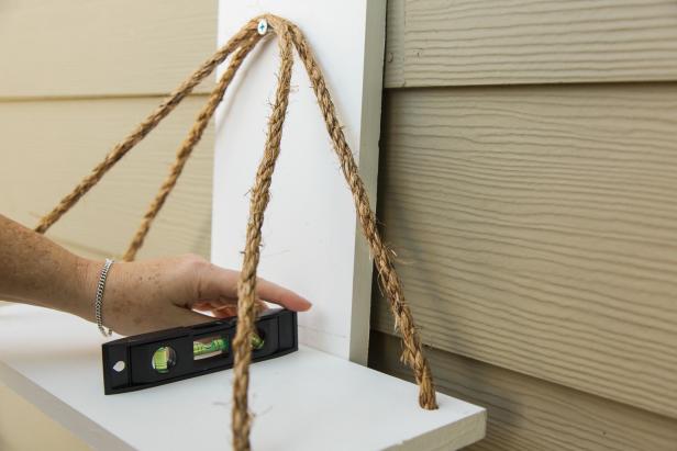It’s important to take the time to get the top shelf adjusted so that it’s the desired height with the back rope first. Once you determine the proper height of the top shelf on the rope, drive the small #4 ¾ inch screws into each grommet slowly with a drill or by hand with a phillips head screwdriver, pushing the screw through the back rope and into the other side of the grommet. Since you used the countersink bit, the screw should lay flat and the grommet will slide nicely up into the hole you drilled into the underside of the board, out of sight. Repeat this step on the other side of the shelf/back rope. Next, focus on the front ropes and getting the top shelf completely level before moving on, driving screws into the grommet/rope, then sliding the shelf down onto the grommet so that the shelf is proper height and level. Once you get it “just so” you can measure down from this top shelf to get the lower shelves spaced correctly and level, as well.