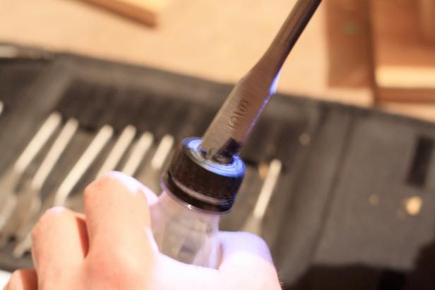 Drill out the top of the bottle cap using a 1/2" or 9/16 inch drill bit, taking care to avoid damaging threads.