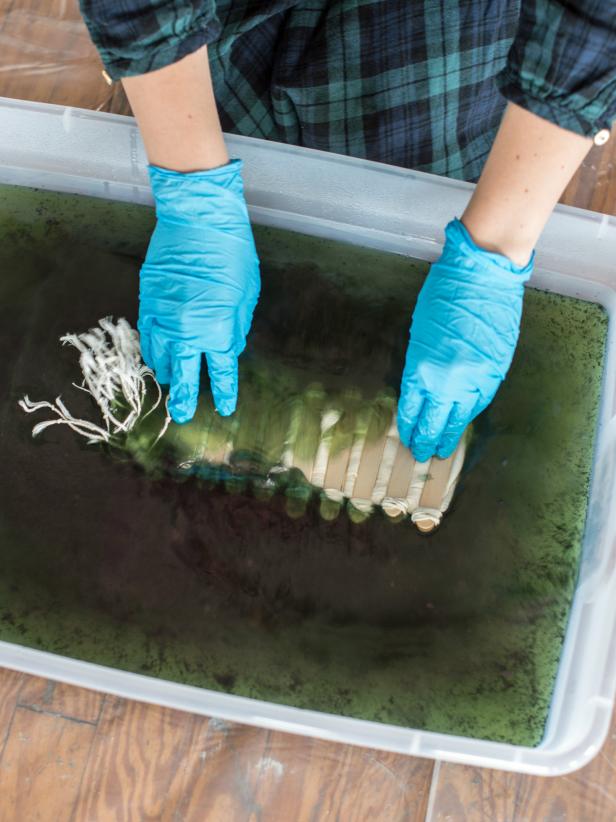 Step 3: Dye FabricWhile wearing gloves, gently ease fabric into dye bath to avoid splashing. Since water is hot, use a large spoon or stir stick to keep fabric submerged in dye bath for sixty seconds. Remove from dye bath and put in second plastic tub to set. Fabric will appear green at first and will turn indigo blue once the air hits it. Tip: For a richer indigo color, repeat dyeing process, allowing the fabric to rest for 30 minutes between each time in the dye bath. Leave dyed fabrics in resists overnight, so pattern and dye can set. Tip: While the dye bath is prepared, dye as many textiles as you can! Cotton t-shirts, linen napkins, tea towels, pillow cases, etc. Natural fiber fabrics will yield the best results.