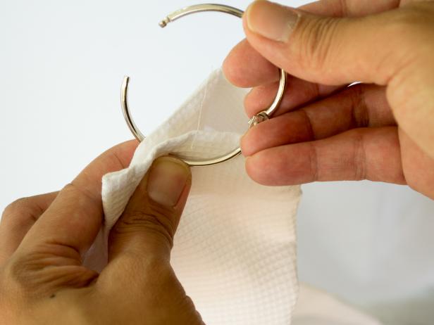 Using the large binder clip, start threading it through the holes at the top of the shower curtains.