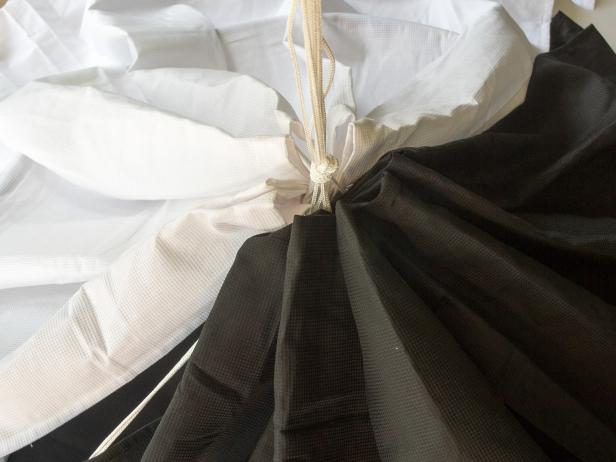 Tie an overhand knot at the base of the gathered shower curtain. Spread the curtain around the hula hoop frame to create the tent.