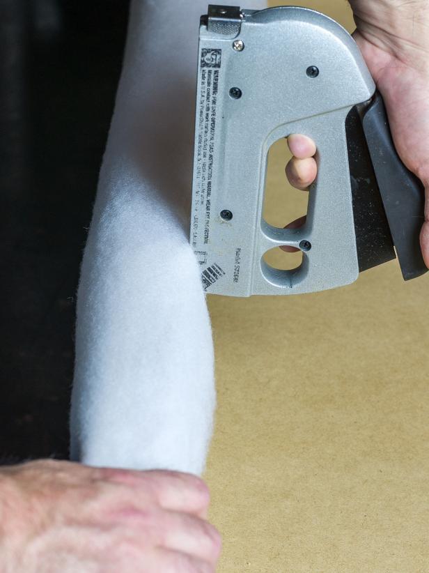 Wrap the sides of the ottoman with batting, stapling on the inside edge of the top and on the bottom.