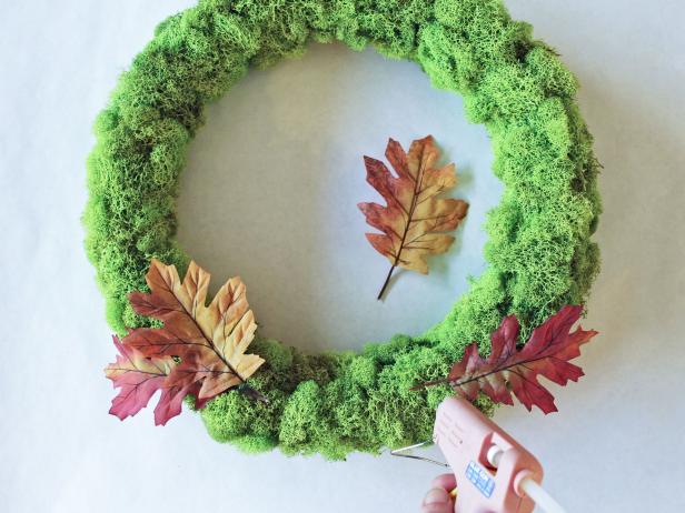 Craft a cheery touch of fall for your front door with a moss-covered wreath form and autumnal ribbon roses.