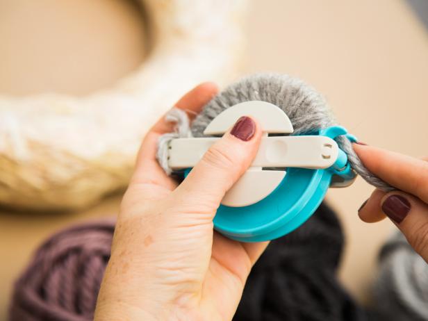 Creating a pom-pom is easy, whether you go “old school” and use your hand or use one of the little devices available at craft stores. If using a device, open one side, then wrap the yarn tightly around edge, pull yarn through to other side and repeat on the other edge.