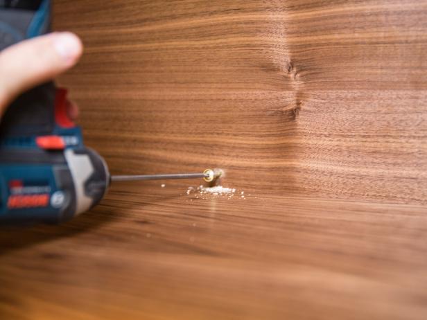 Using the 2 1/2" Cabinet lags, pre-drill four holes that align with studs, and attach shelf unit to the wall at desired height.