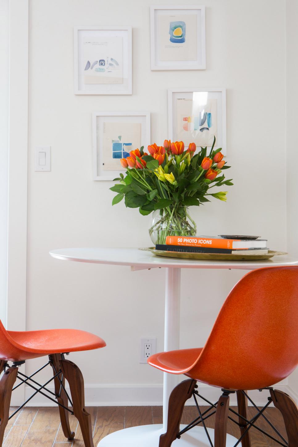 Orange Accessories Brighten Eating Nook Small White Table with Vase of Orange Tulips and Orange Chairs