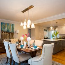 Open Floor Plan Dining Room With Pendant Light Chandelier Over Nailhead Trimmed Chairs and Floral Centerpiece