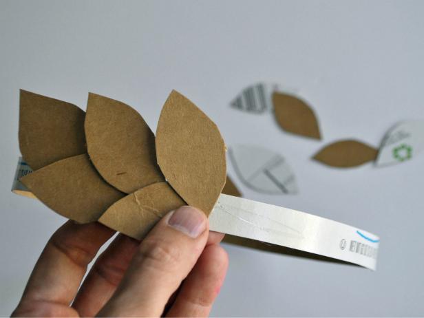 Cut open cereal box. Cut one long strip of cardboard and 20-25 leaves. Take cardboard strip and hold around head of the costume wearer to gauge size. Cut to length and use hot glue gun to glue ends together to create a headband. Hot glue leaves onto front half of the headband. Spray paint wreath gold.