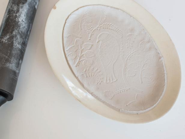 Carefully place clay inside a platter, bowl, or plate in desired shape. Gently press clay into the form of platter. Don' t press too hard or the design will be damaged. Cut rough edges with plastic knife and smooth out with a finger. The edges will be sanded once clay is dry, so it doesn't have to be perfect at this stage. Allow clay to dry until hardened per instructions (usually about 24-72 hours).