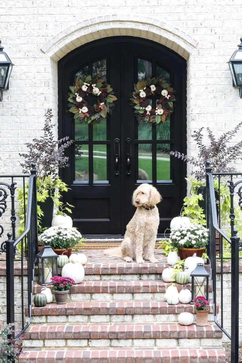 “I was inspired by the existing landscaping around the porch,” says Leslie Davis of Paper Daisy Design. “When the maple tree just outside the front door changes colors, it becomes a vibrant a crimson color. I wanted to highlight the purples and deep reds and work with the ivory tones of the brick,too.”“I love a pulled-together look that coordinates with your house and landscape,” Leslie says. “Consider what fall looks like in your region or yard and mimic it for a more natural design. [For example,] we have three mature magnolia trees in the front yard and the use of the magnolia leaves in the wreaths seem right at home.”
