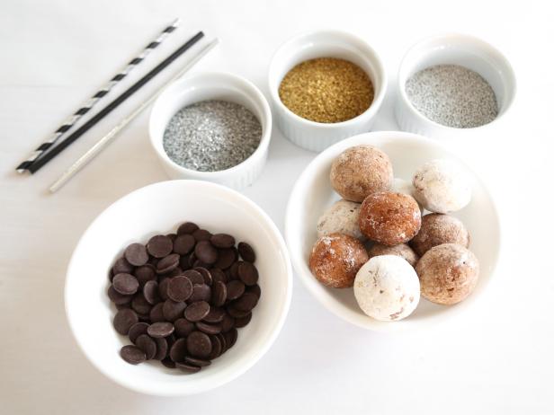 Cover a work surface with a large sheet of parchment paper.

Have all supplies ready to hand before melting the chocolate: donut holes, pop sticks, and sparkling sugars placed in separate bowls.

12 donut holes
6 ounces semisweet or dark chocolate
1/2 cup gold sanding sugar
1/2 cup silver sanding sugar
1/2 cup 3mm silver dragees
1/2 cup 3mm gold dragees
12 lollipop sticks or sturdy paper straws
