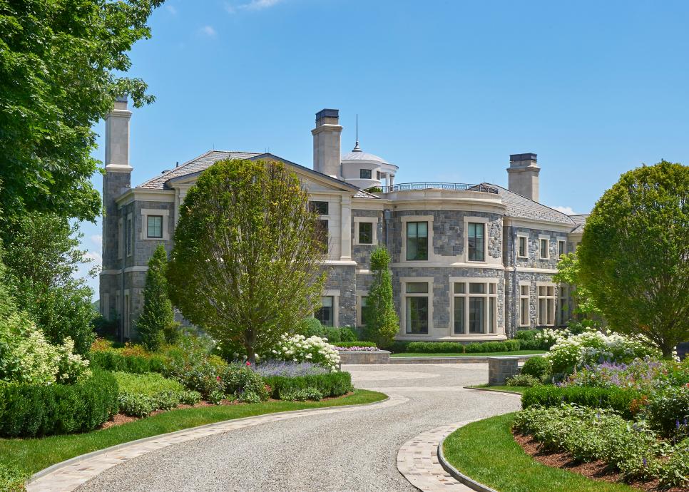 Grand Gray Stone Home Exterior With Gravel Driveway and Lush Planted Front Yard Gray Stone Exterior