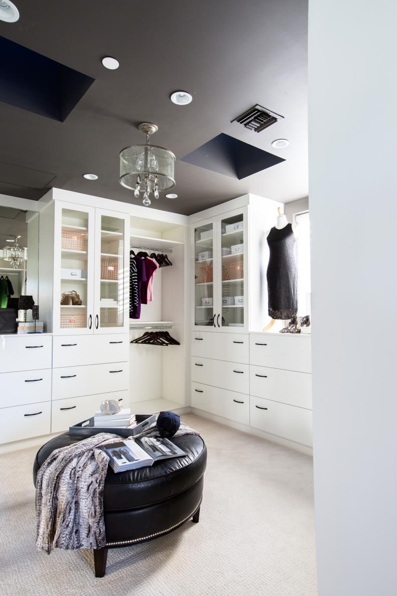 Stylish, efficient master closet has an ottoman and space for storage