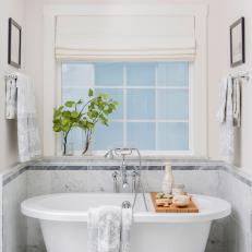 Master Bathroom With White Pedestal Bathtub and Marble Tile